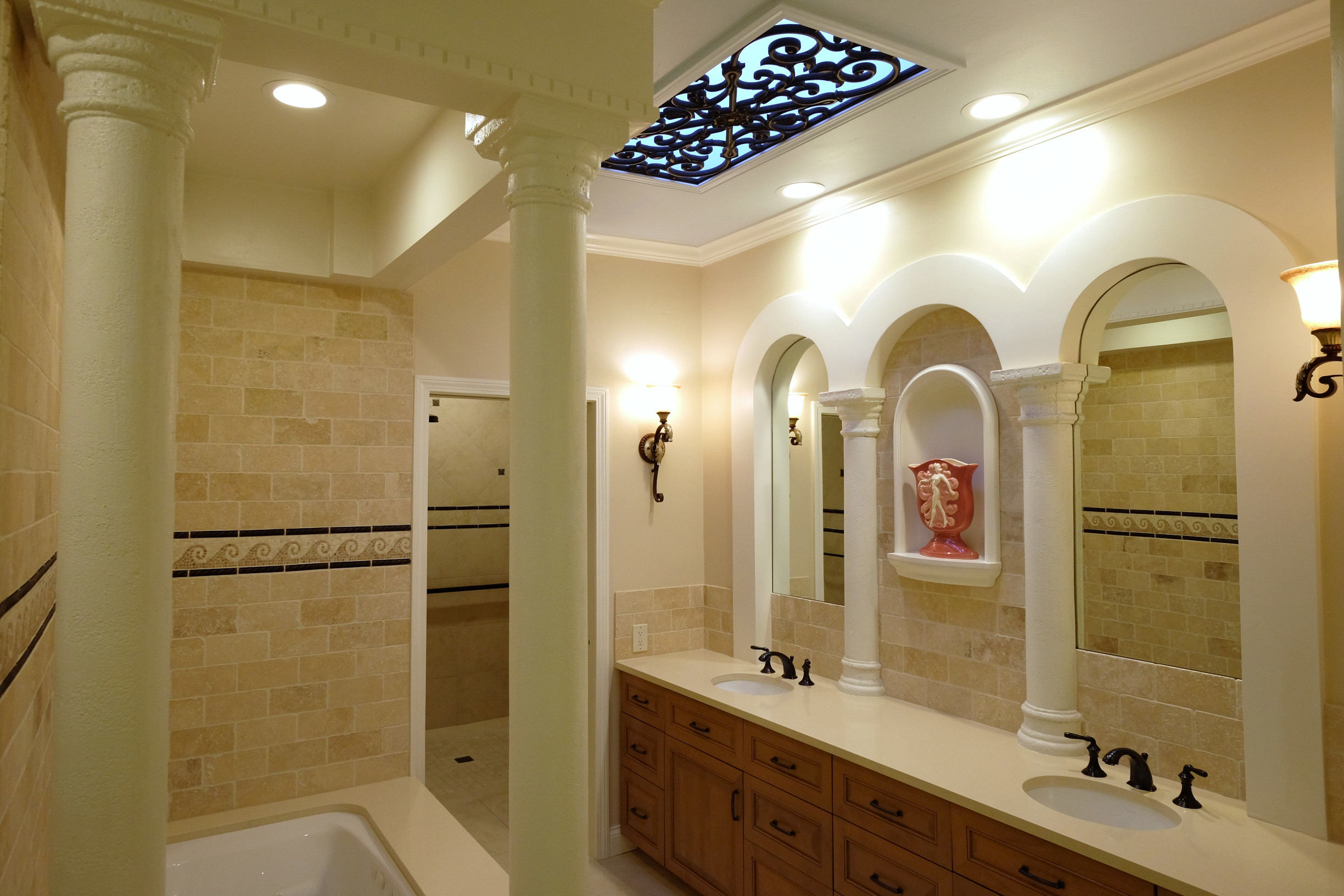 Roman bath with travertine, columns, tile mosaic, and bronze accents